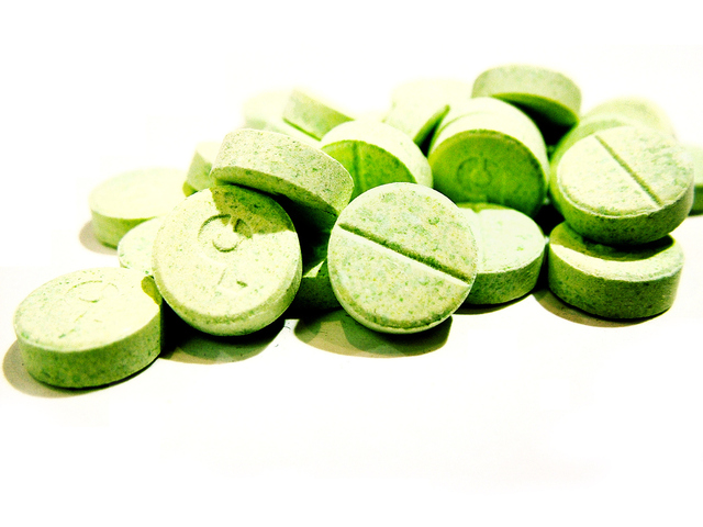 zelené pilulky plné vitamínů na bílém podkladu 